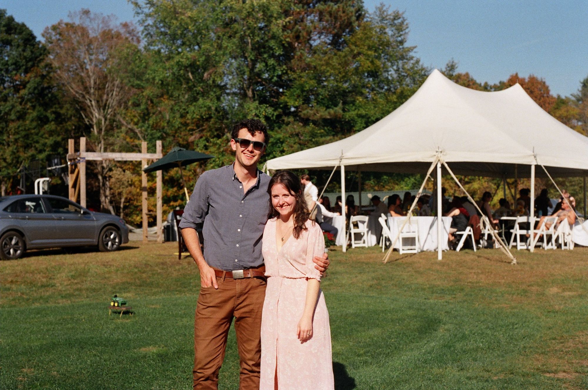 The Floyds standing together on a sunny lawn, with a white party tent and autumn trees behind them